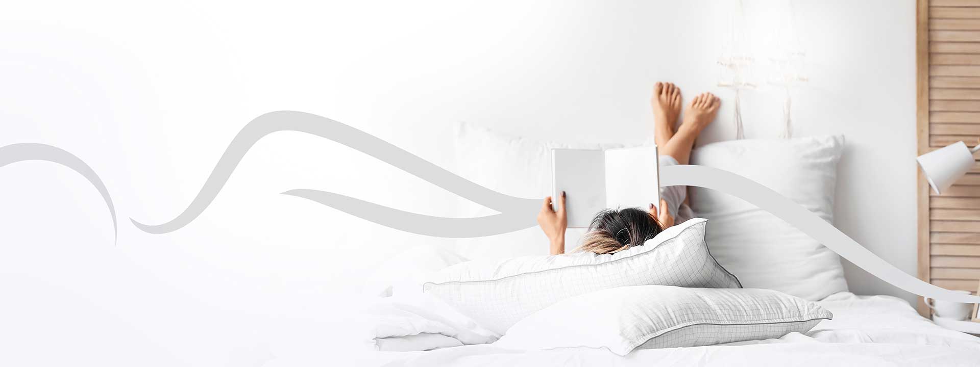 Frau liegt gemütlich im Bett und liest